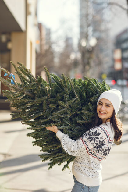 市场优雅的女孩买了一棵圣诞树帽子松树卷发