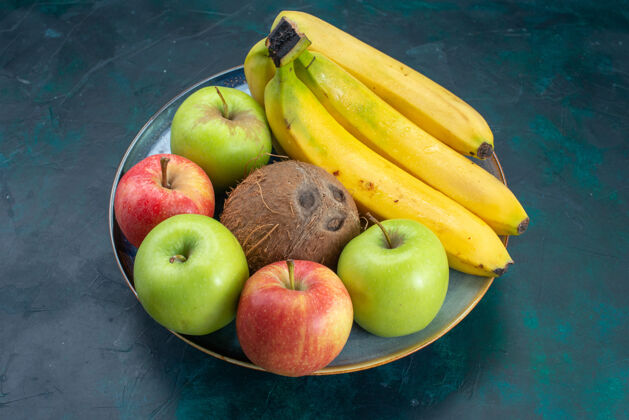 热带前视不同水果组成椰子苹果和香蕉深蓝色桌上水果新鲜醇厚异国情调热带不同水果新鲜