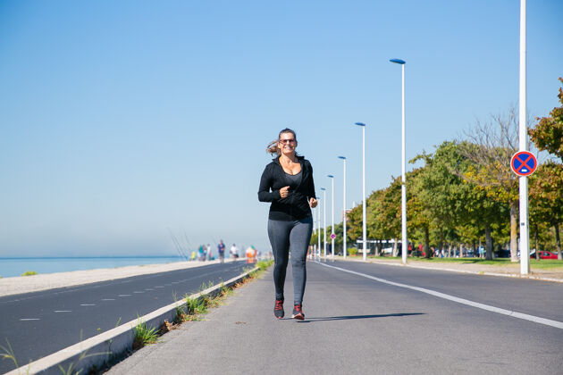 中年专注的成熟女性 穿着健身服 在河堤边慢跑 享受晨跑正面视野 全长积极的生活方式理念兴奋跑步退休
