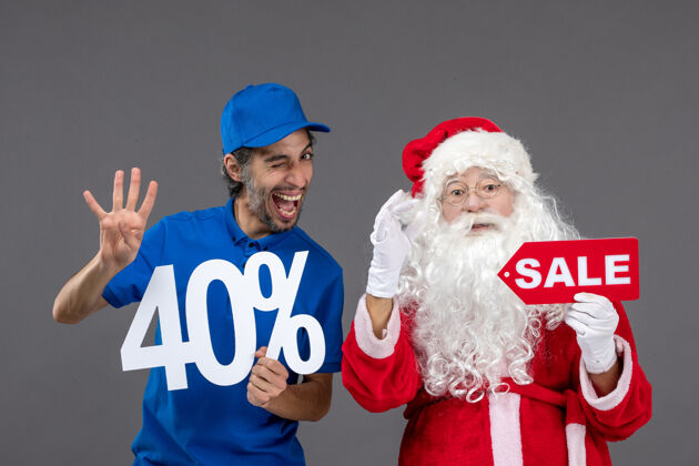 销售圣诞老人的正面图 灰色墙上的男性信使手持销售横幅圣诞老人前面举行