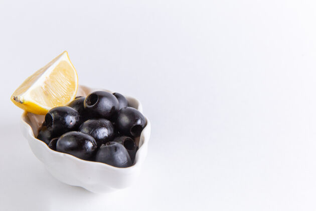 多汁正面近距离观看新鲜黑橄榄与柠檬片对白色表面彩色照片食品植物油油橄榄饮食