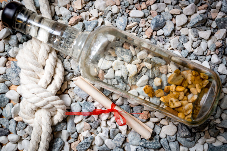 沙子信的特写镜头 瓶子和海洋结躺在卵石上海边地中海瓶子