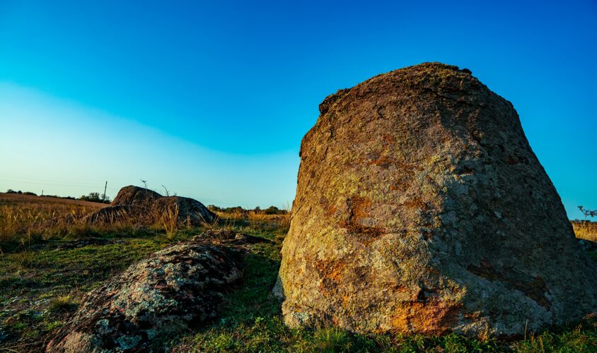 石头在风景如画的乌克兰和美丽的自然中 一片充满温暖阳光的草地上 覆盖着植被的巨大古老石头矿物堆积物草地海岸田野