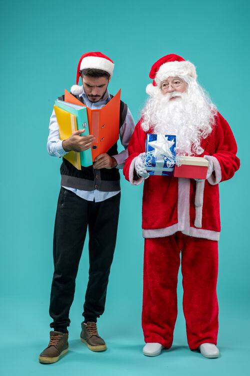 蓝色圣诞老人和年轻的男性和礼物在蓝色的桌子上视图正面圣诞
