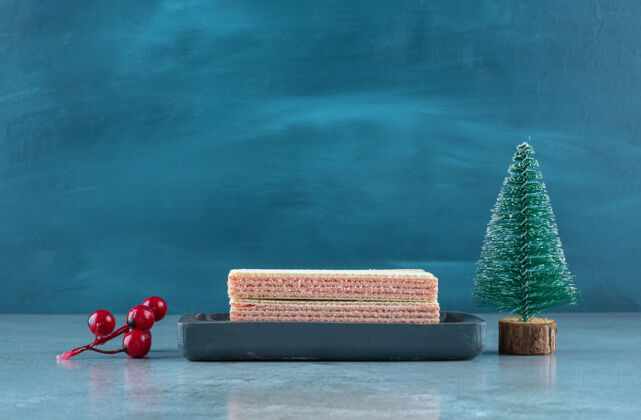 圣诞树草莓奶油馅饼在一个小托盘旁边的大理石表面圣诞饰品开胃美味威化饼干