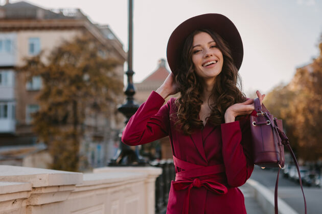 套装穿着紫色西装的漂亮时髦女人走在城市街头 春夏秋冬时节时尚潮流戴着帽子 手拿钱包时尚秋天套装