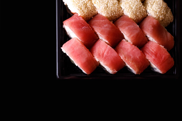 空白寿司递送在一个黑色背景的一次性盒子里的一套卷日式文化外卖