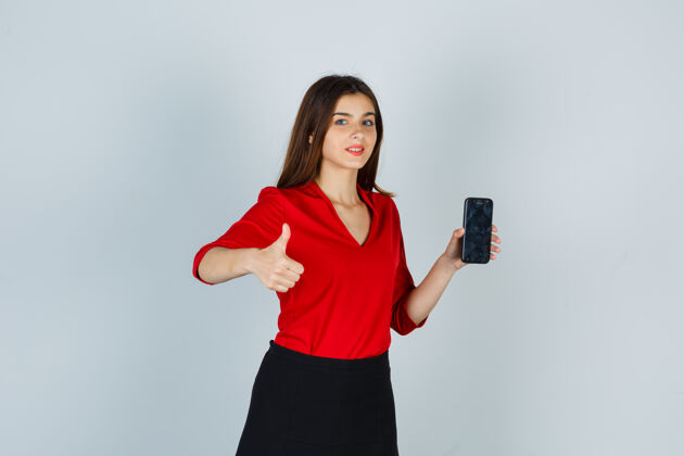 漂亮穿着红衬衫拿着手机的年轻女士竖起大拇指正面女性漂亮