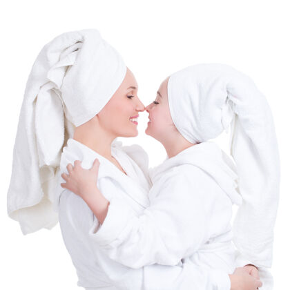 女快乐的母亲和穿着白色晨衣的小女儿的肖像互相看着-孤立年家庭长袍
