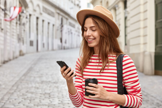漫步美丽的游客漫步在城市街道上 使用在线导航器寻找正确的道路 手持手机电话水平时尚
