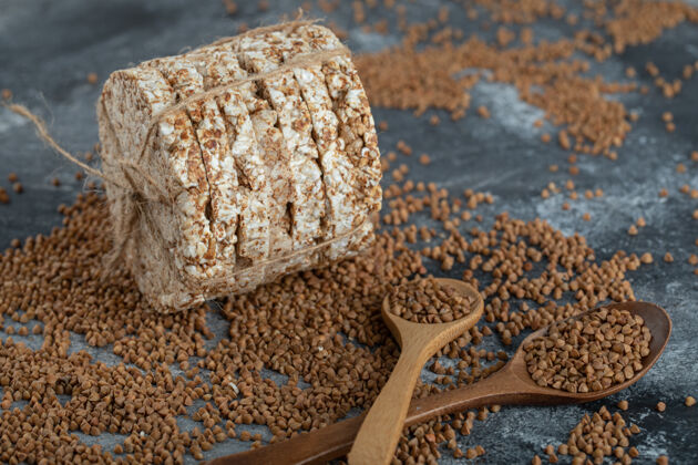 荞麦生荞麦和脆面包放在大理石表面木制脆的种子