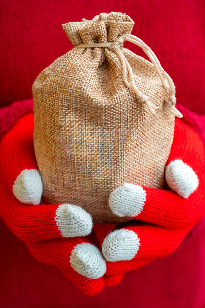 女性穿着暖和毛衣和红色针织手套手持圣诞礼品袋的女性袋子包包