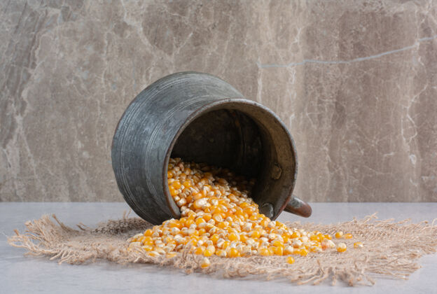 配料把玉米粒倒在大理石上的一块布上的金属罐玉米布料谷物