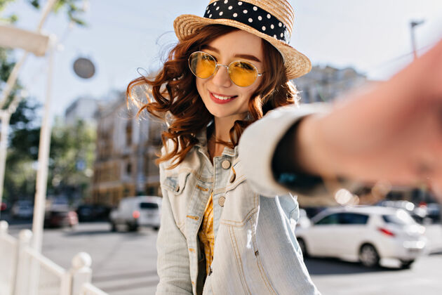 美丽迷人的白种女孩 红色卷发 在街上自拍穿着牛仔夹克的快乐小姐 在城市里欢笑城市华丽优雅