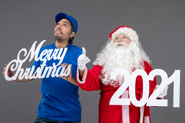人圣诞老人与男信使举行圣诞快乐和2021年板灰墙正面视图前面快乐庆祝