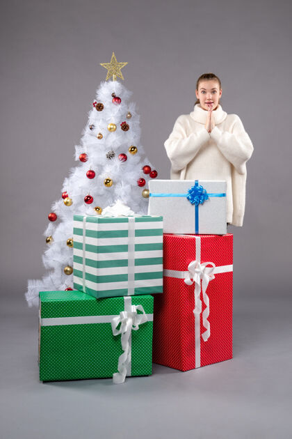 礼物年轻的女性在灰色的圣诞礼物周围衣服盒子包