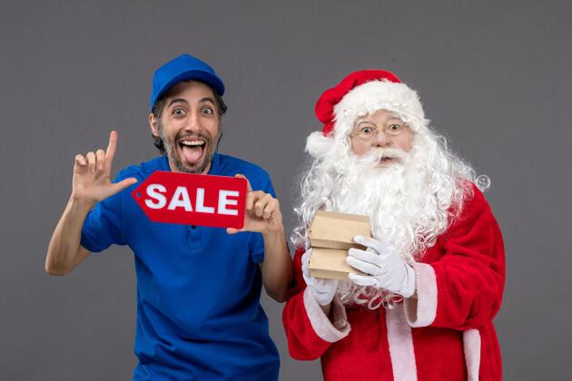 地板圣诞老人的正面图 男信使手持销售横幅 灰色墙上有食品包装帽子圣诞老人人