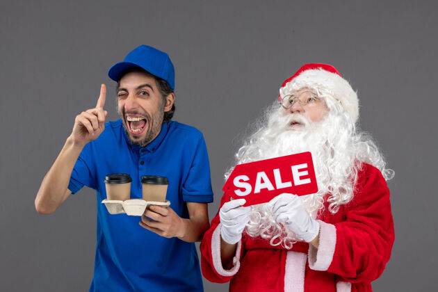 快乐圣诞老人的正面图 男信使拿着售货笔 灰色墙上挂着咖啡庆祝圣诞老人举行