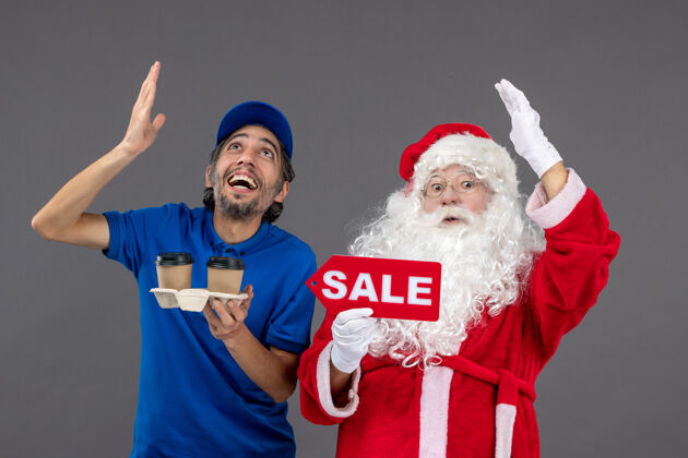 庆祝圣诞老人的正面图 男信使拿着售货笔 灰色墙上挂着咖啡销售人圣诞