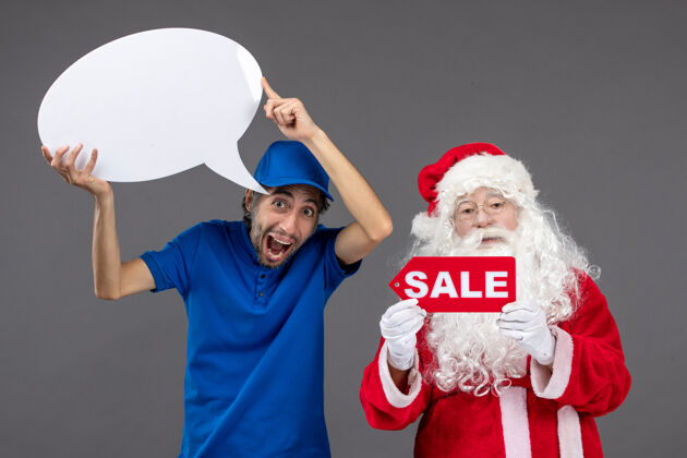 快乐圣诞老人与男信使手持白色标志和灰色墙上的销售横幅的正面视图男销售人