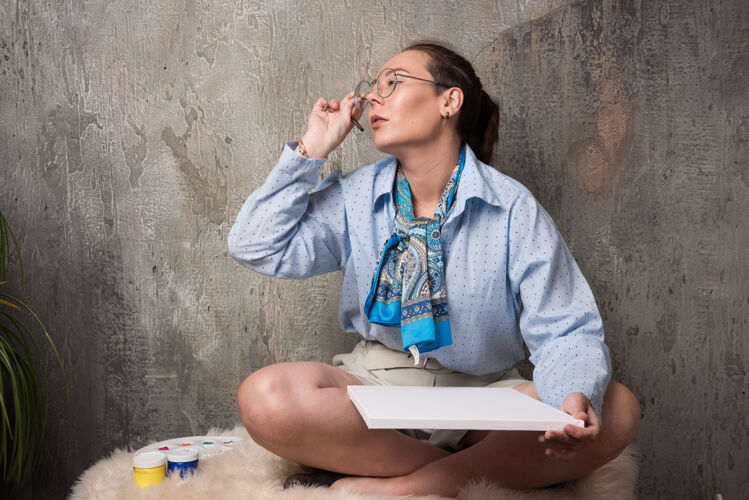 画布坐在大理石背景上用帆布和画笔画画的女人高质量的照片大理石女士油漆