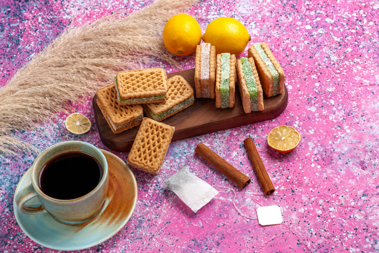 粉色半顶视图美味的三明治饼干柠檬茶和肉桂粉办公桌上杯子半顶美味