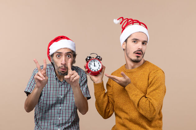 两个男人正面图两个男人一个用手指显示时间 另一个拿着闹钟 背景是米色的钟帽子男