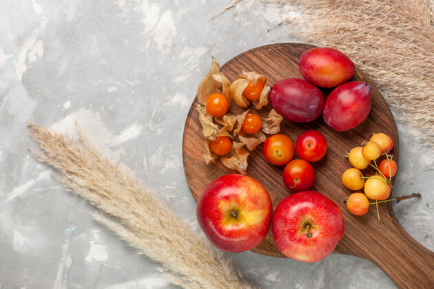 苹果顶视图不同形状的李子酸和新鲜水果和苹果放在浅白的桌子上苹果健康水果