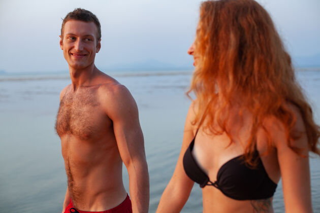 自然年轻性感浪漫的情侣在夏天的沙滩上快乐地穿着泳装玩阳光男人肖像