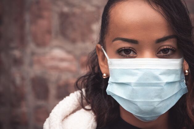 黑一个戴着医用面罩的年轻女子的选择性聚焦镜头-保持安全的概念防护流行病医学