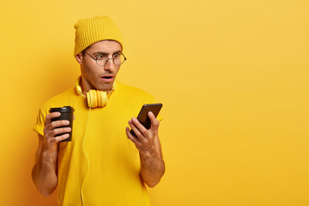 帽子穿着黄色套装 戴着眼镜的时髦男人 使用智能手机眼镜印象深刻饮料