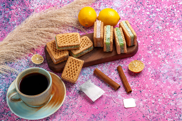 粉色半顶视图美味的三明治饼干柠檬茶和肉桂粉办公桌上杯子半顶美味