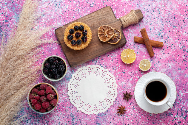 粉顶视图树莓和黑莓在小壶内与茶肉桂杯浅粉红色的表面里面Berry壶