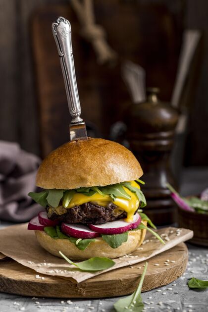 汉堡包前视图切肉板上的芝士汉堡与刀食物垂直美味
