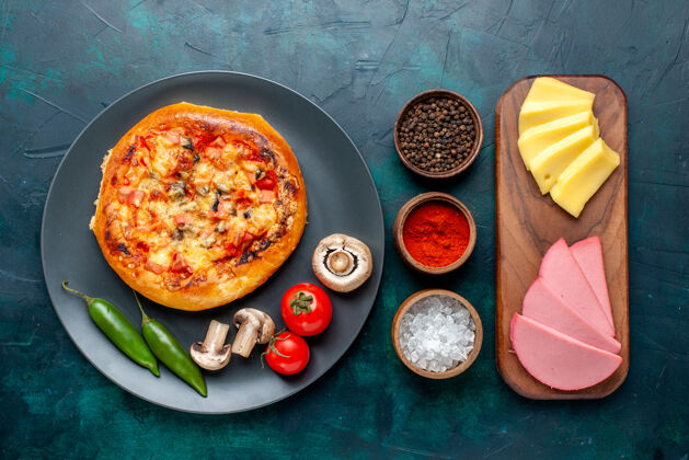 烘焙小奶酪比萨饼的俯视图 圆形比萨饼由深蓝色表面的调味品和奶酪组成午餐面团餐厅