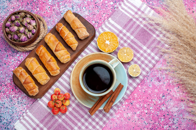 棕色在浅粉色的桌子上可以看到美味的小面包圈 还有一杯茶和柠檬面团糕点美味