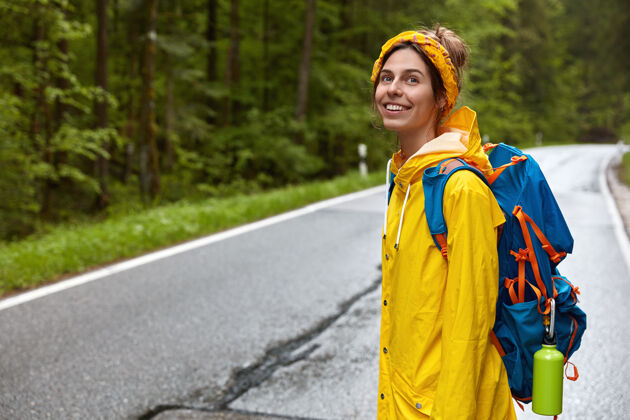 背包背着背包的积极的年轻女子 侧身站在镜头前 走过马路自然水平自由