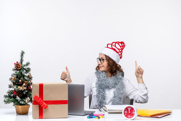 坐着正面图：年轻的女工坐在她工作的地方 在白色的背景下微笑着微笑圣诞节笔记本电脑