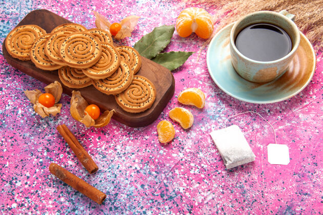棕色半顶视图圆形甜饼美味的小饼干 粉红色桌子上放着一杯茶和橘子小半顶粉红色