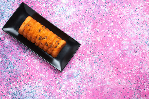 美味在粉红色桌子上的黑色蛋糕锅里俯瞰美味的烤蛋糕黑色接近烘焙