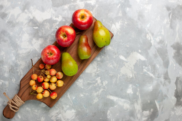 红色在浅白的桌子上俯瞰新鲜的红苹果和甜樱桃和梨水果浅白色顶部