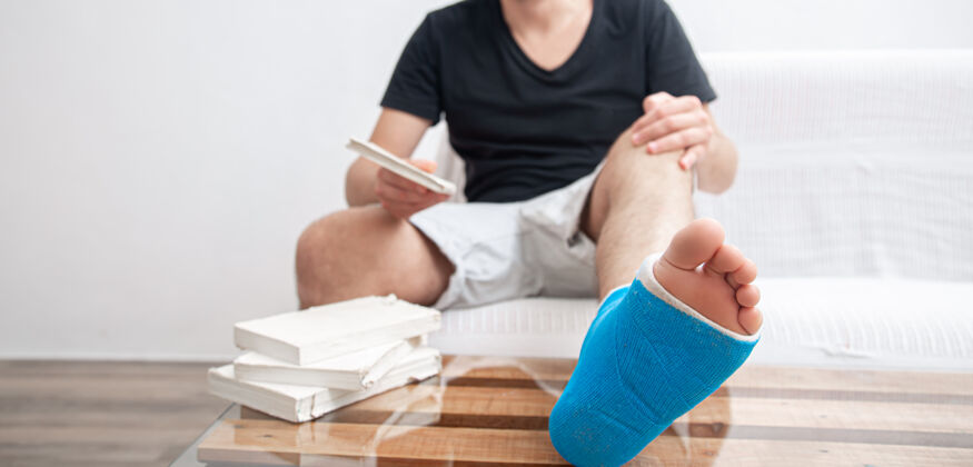 下男子腿部骨折用蓝色夹板治疗脚踝扭伤伤在家看书康复脚踝脚骨折