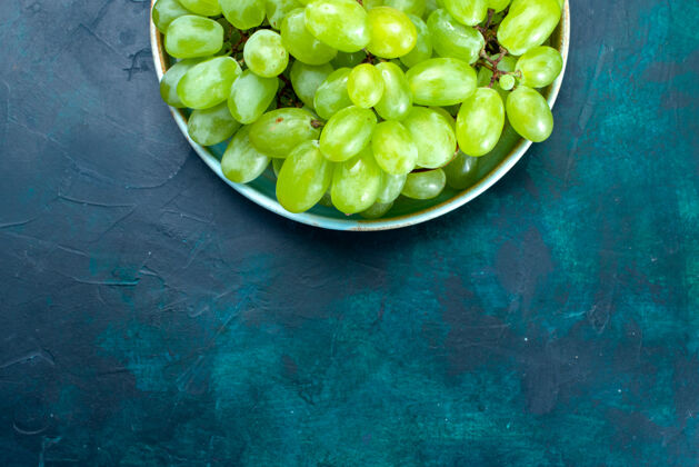 健康在深蓝色桌子上的盘子里 可以俯瞰新鲜的绿色葡萄 醇香多汁的水果葡萄深色磨碎