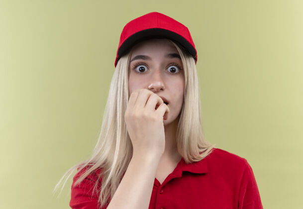 年轻一个戴着红色t恤 戴着帽子的年轻女孩把她的手放在孤立的绿色背景上T恤嘴绿色