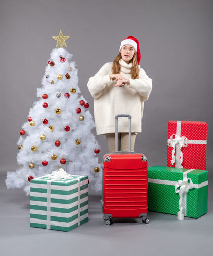 行李前视图女孩拿着手提箱戴着圣诞帽问时间帽子圣诞节旅行