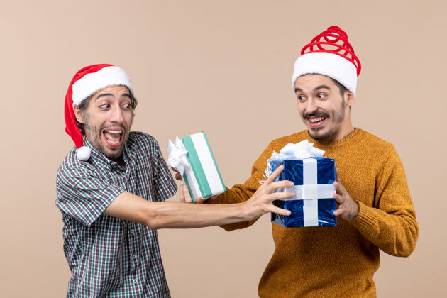 混乱前视图两个困惑的家伙交换他们的圣诞礼物米色孤立的背景风景男人男