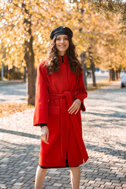 户外迷人的时尚微笑的女人卷发漫步在公园穿着温暖的红色外套秋季时尚 街头风格 戴贝雷帽装束黄色苗条