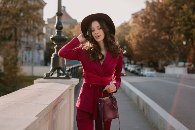 年轻酷酷靓丽的时尚女人穿着紫色西装走在城市街头 春夏秋冬时节时尚潮流戴着帽子 手拿钱包户外女士户外