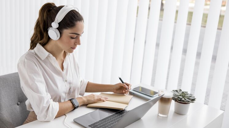 笔记本电脑女商人用笔记本电脑和耳机工作议程专业人士耳机