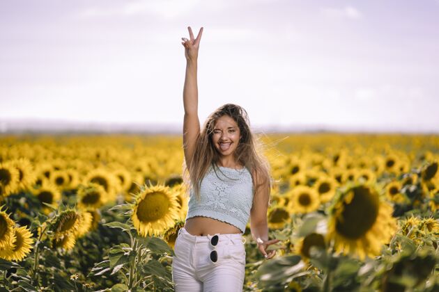 成人阳光明媚的日子里 一位白人年轻女性在向日葵的田野里摆姿势的水平镜头脸草地开花
